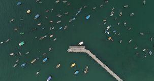 Aerial video, ascending  with drone over the sea with boats. Artisan fishermen close to a pier in Chorrillos district in Lima peru.