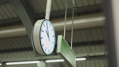 Public train station clock, appointment at the station, time rush hour period, working hours weekday business running, big clock hanging down from train platform ceiling, evening night time