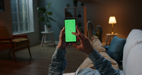 Close up shot of guy relaxing on couch at night, using smartphone with chroma key green screen and doing various gestures on display - technology, communications concept 4k template