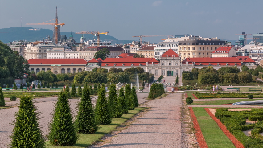 Belvedere palace with beautiful floral garden and walkways timelapse, Vienna Austria. Blue sky with clouds on sunny day. Green lawn and historic buildings