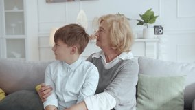 Family portrait of attractive blonde grandmother with cute teenager boy smiling together posing indoors. Grandma and grandson. Photoshoot. Apartment.