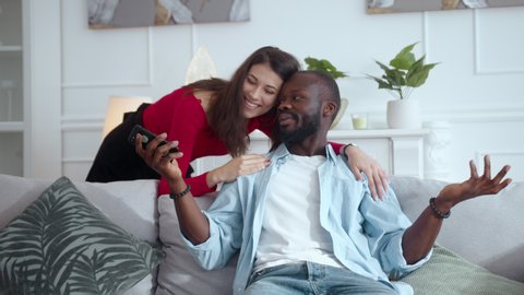 Excited multi-race happy couple make peace after conflict luck afro-american man winning online bet lottery prize celebrating family victory together. Fun concept.