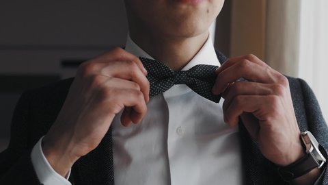 Businessman straightens bow tie close up. Portrait of man