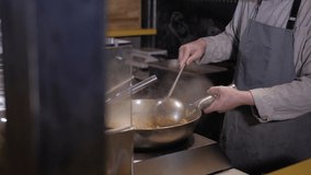 Close-up of chef cooking a noodle with meat and vegetables in wok pan.Cooking process. Cook tosses food. Asian food preparing concept.