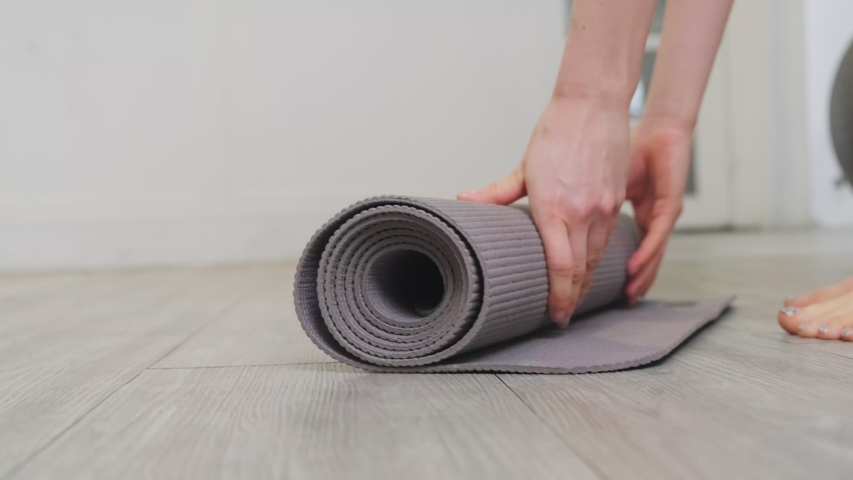 B roll shot of woman roll out yoga mat for preparation. Close up view on hand when open mat. Young beautiful fit sport woman work out by exercise yoga in living room at home during covid19 pandemic. | Shutterstock HD Video #1056856904