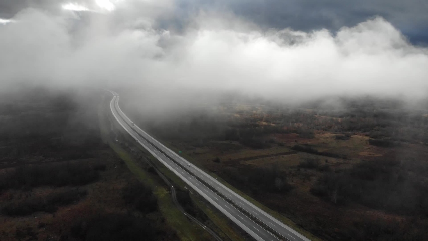 Drone flying down from above the clouds approaching the highway in Croatia during summer season. Vacation transportation truck car auto moto motorway speed