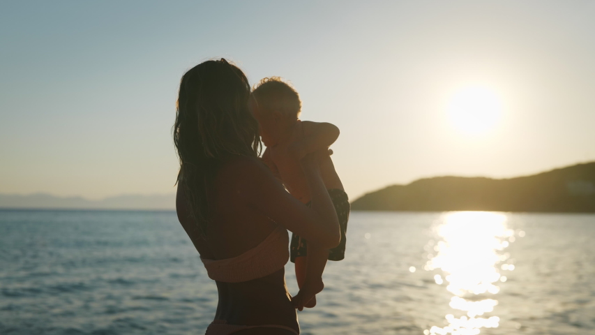 Authentic close up shot of an young neo mother is keeping on her arms and playing with a newborn baby on a seaside beach at sunset during holiday vacation. Royalty-Free Stock Footage #1056868742