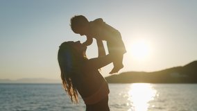Authentic close up shot of an young neo mother is keeping on her arms and playing with a newborn baby on a seaside beach at sunset during holiday vacation. - Powered by Shutterstock - Get 15% off with code: PIKWIZARD15