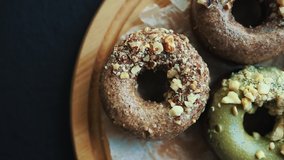 Fresh baked donuts filmed from above.Delicious bakery products in pastry cafe served on wooden plate in cafe for lunch.Enjoy traditional Dutch doughnuts with icing & nuts for coffee break meal