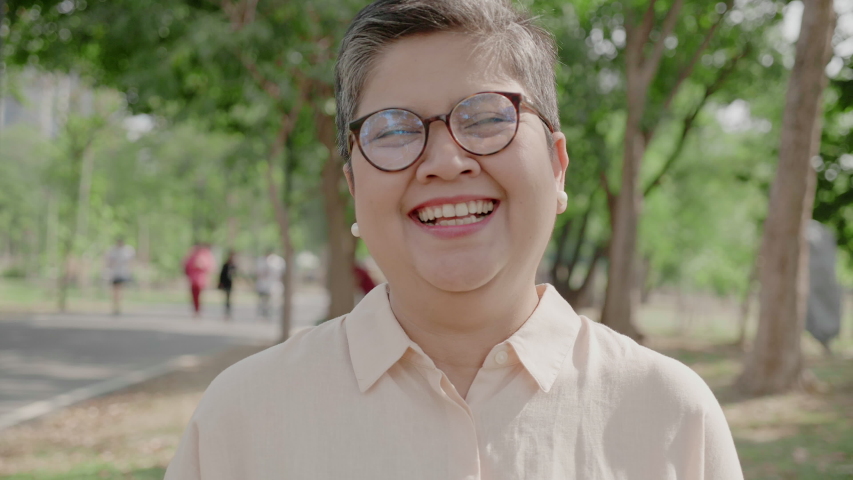 Close up of asian elderly grandmother face smiling happy. Senior woman standing in park with beautiful nature. Eyeglasses help make  vision of the elderly. Concept International Day of Older Persons  Royalty-Free Stock Footage #1056871439