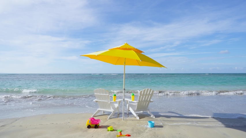 Summer vacation at the hotel on the beach with children. Beautiful blue sea and beach accessories. Sun umbrella and deck chairs on the beach. Royalty-Free Stock Footage #1056871823