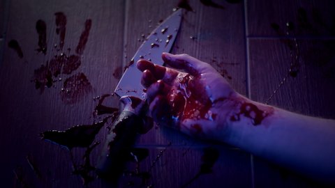 Bloody female hand with knife. Body of dead person on floor of violent crime scene in flashing red and blue light of police car or ambulance. Blood, bloody palm prints. Murder, suicide concept