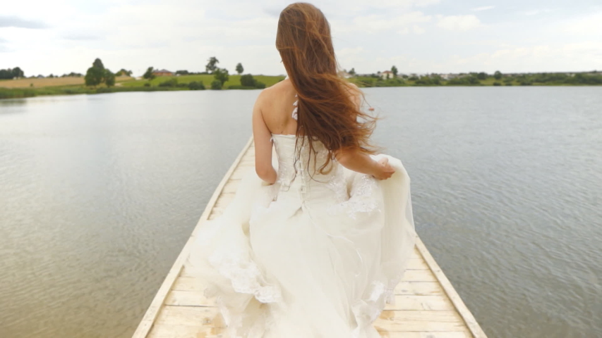 A woman in a wedding dress runs away and jumps into the water. Royalty-Free Stock Footage #1056879032