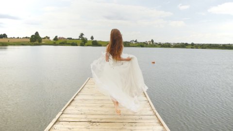 A woman in a wedding dress runs away and jumps into the water.
