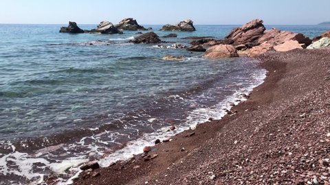 Wild nudist beach on the sea coast. Close-up view of waves and pebbles, rocks and cliffs. Crvena Glavica, Montenegro