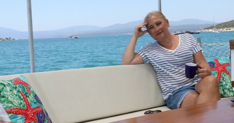 Portrait of a caucasian female tourist woman on luxury yacht relaxing and looking around at summer vacation.