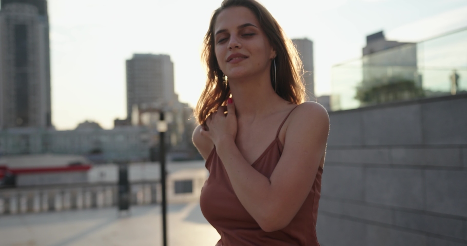 Beautiful brunette young woman model wearing brown dress and posing on the street.