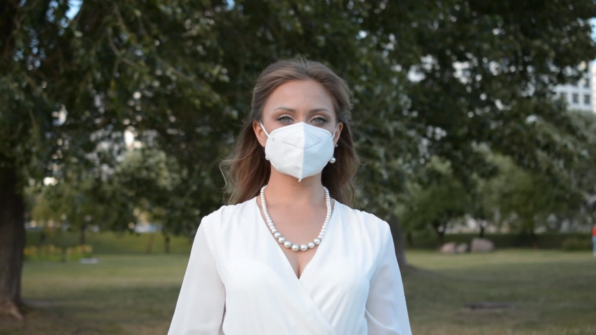 Fashion young woman in a medical protective mask on her face outdoor