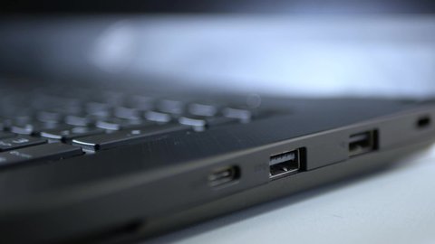 Caucasian man inserting an usb pen drive in to a gaming laptop computer.