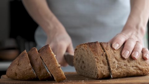Woman cutting bread at the kitchen. Slicing bread to make a sandwich. Cooking process 4k resolution footage