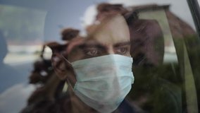 A man male sitting in the car wearing a face protective mask looking outside through the glass window amid Corona virus COVID 19 epidemic or pandemic - Powered by Shutterstock - Get 15% off with code: PIKWIZARD15