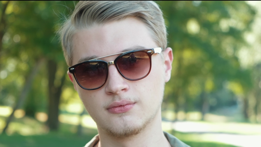 Close up footage of young man wearing sunglasses and looking confident at the camera.