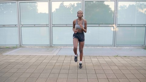 Slow motion shot of young woman with headphones jogging in place Video stock