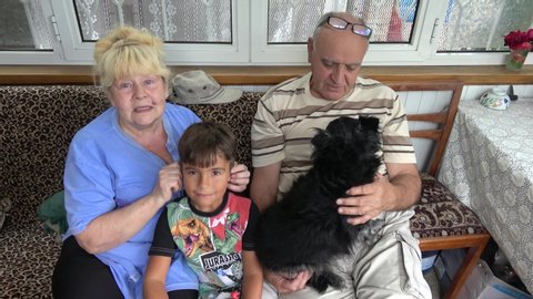 Kherson, Ukraine - 15th of July 2020: 4K Multi generational video of grandparents and grandson posing for family picture on veranda with a dog
