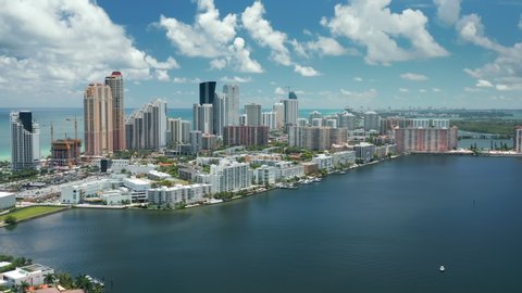 Impressive panoramic aerial of beautiful Miami city skyline with ocean and sky with white clouds on motion background. Beautiful Bay Area with blue waters and colorful vibrant modern buildings, 4K