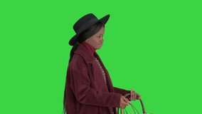 Pretty African american fashion girl in coat and black hat strolling with shopping bags on a Green Screen, Chroma Key.