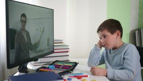 online teaching, schoolboy at home watching a video broadcast with his teacher explains lesson on video communication, isolation period