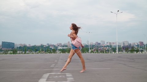 Athletic Young Woman in short denim shorts with a perfect slim figure walks in a beautiful gait and waves her foot up while taking off her shoes.