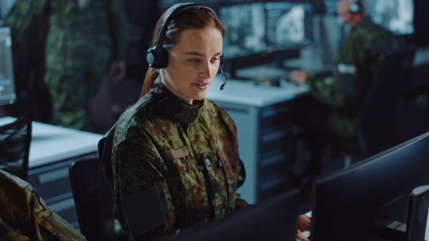 Beautiful Female Military Surveillance Officer in Headset Working in Central Office Hub for Cyber Operations, Control and Monitoring for Managing National Security, Technology and Army Communications. Royalty-Free Stock Footage #1056907664