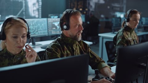Military Surveillance Team of Officers in Headsets Working in a Central Office Hub for Cyber Operations, Control and Monitoring for Managing National Security, Technology and Army Communications.