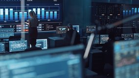 Software Engineers Working in a Room with a Big Screen in a Modern Monitoring Office with Live Analysis Feed with Charts. Monitoring Room Big Data Scientists and Managers Sit in Front of Computers. - Powered by Shutterstock - Get 15% off with code: PIKWIZARD15