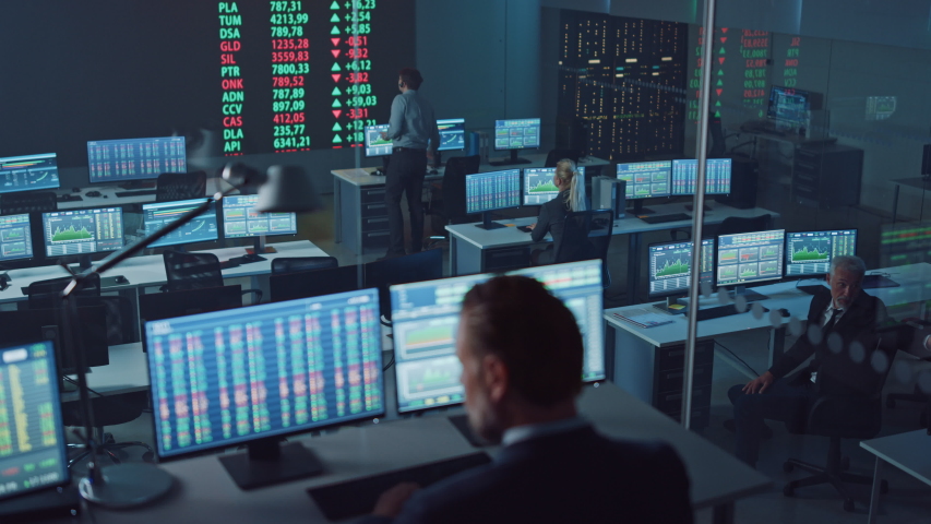 Professional Financial Data Analysts Working in a Modern Monitoring Office with Live Analytics Feed on a Big Digital Screen. Monitoring Room with Finance Specialists Sit in Front of Computers. Royalty-Free Stock Footage #1056907799