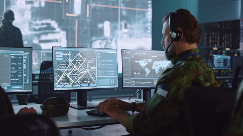 Military Surveillance Officer Working on a City Tracking Operation in a Central Office Hub for Cyber Control and Monitoring for Managing National Security, Technology and Army Communications. Royalty-Free Stock Footage #1056907826