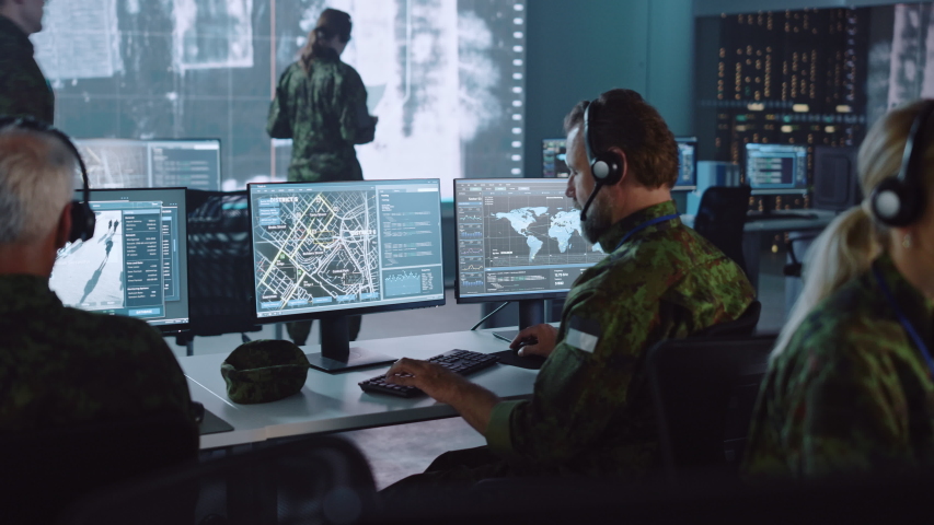 Military Surveillance Officer Working on a City Tracking Operation in a Central Office Hub for Cyber Control and Monitoring for Managing National Security, Technology and Army Communications. Royalty-Free Stock Footage #1056907829