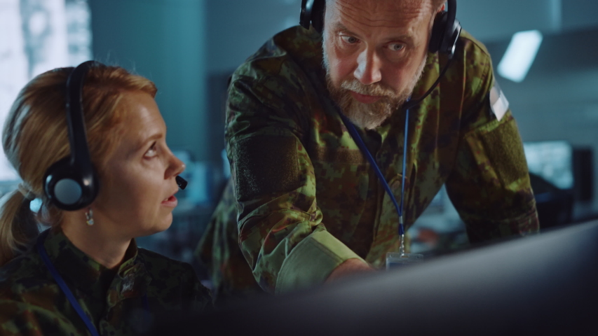 Military Surveillance Officers Talking Next to a Computer Screen in Central Office for Cyber Operations, Control and Monitoring for Managing National Security, Technology and Army Communications. Royalty-Free Stock Footage #1056907838