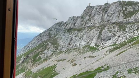 Paraglider flying over Mount Pilatus seen through window of railcar at Alpnachstad, Switzerland. High quality 4k footage