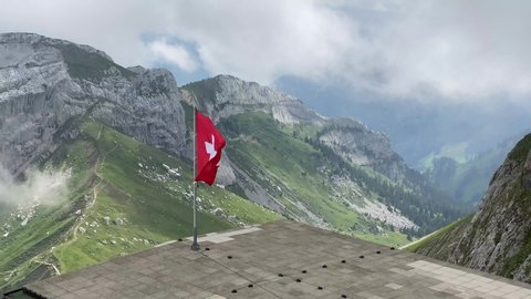 Swiss flag in wind against beautiful mountains at pilatus, Switzerland. High quality 4k footage