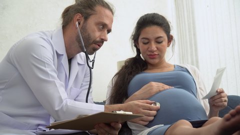 gynecologist doctor with stethoscope listening and examining to pregnant woman baby heartbeat in medical office at at hospital