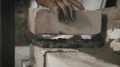 Construction worker or mason laying bricks and creating walls. Bricklayer laying bricks to make a wall. Building a cement block wall for a house.