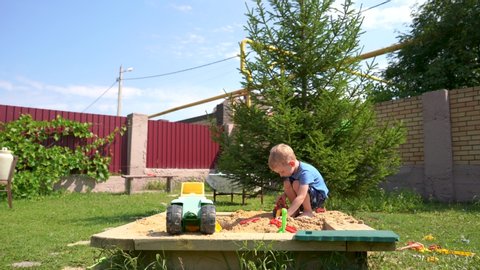 small blond boy is playing in the sandbox
