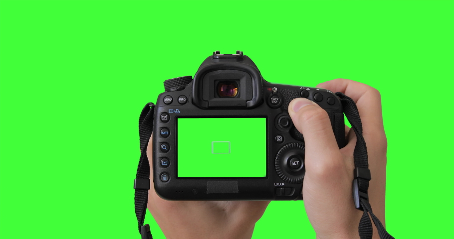 Professional photographer or filmmaker adjusts the DSLR camera settings before shooting. Isolated gear is holding by two hands. Keyed green screen.