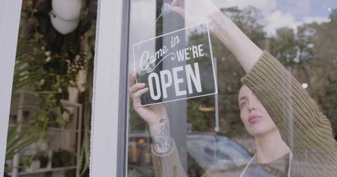 Small business entrepreneur Store Owner Turning Open Sign In Shop Doorway window