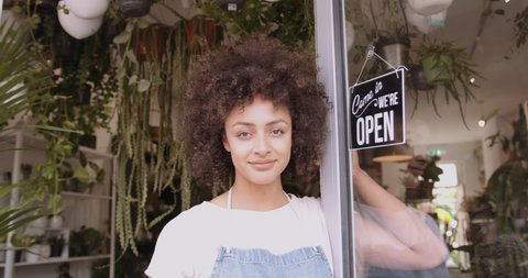 Portrait of Small business entrepreneur afro American female Store Owner Turning Open Sign In Shop Doorway and smiling