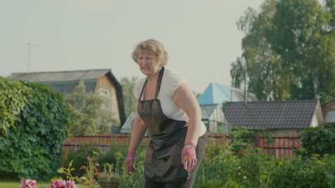 Elderly woman with a sore back. Grandmother with a sore back works in the garden