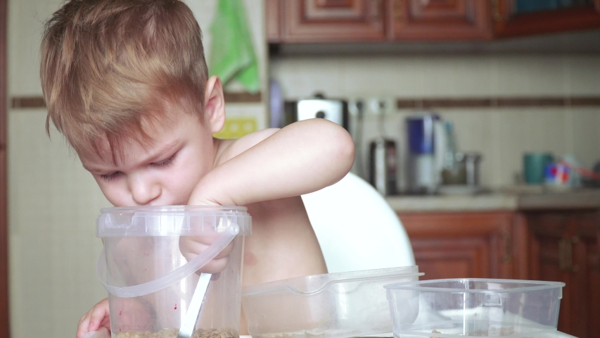 Boy playing with peas and beans and plastic containers