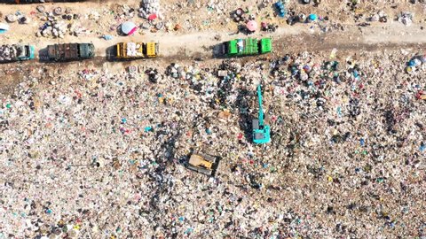 Time lapse of Aerial top view of A Huge Waste, garbage, dump, rubbish landfill. A landfill compactor, group of workers sort out the garbage in the landfill. Trash trucks dump waste polluting products.